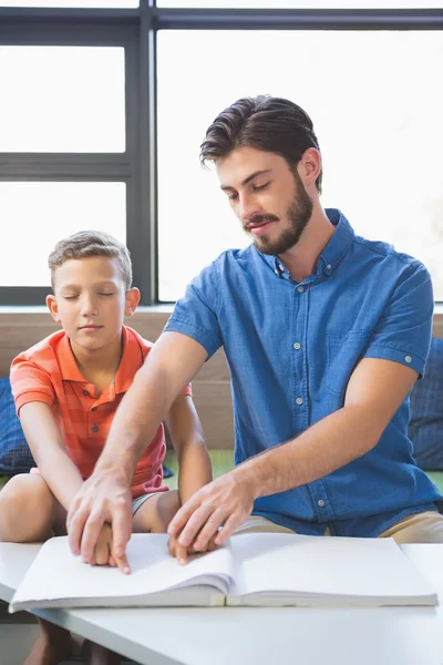 Teacher assisting blind student in library — Stock Photo, Image