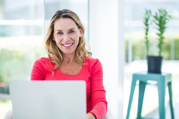 Kvinna ler när du använder laptop — Stockfoto