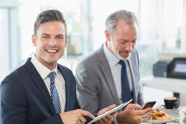 Dois empresários usando tablet digital e telefone celular — Fotografia de Stock