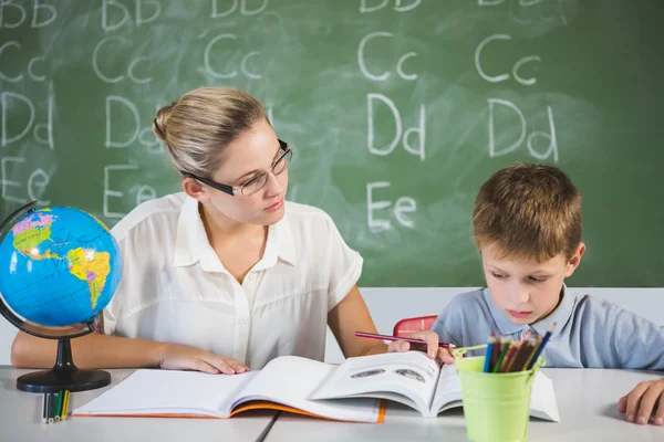 Insegnante aiutare un ragazzo con i suoi compiti in classe — Foto Stock