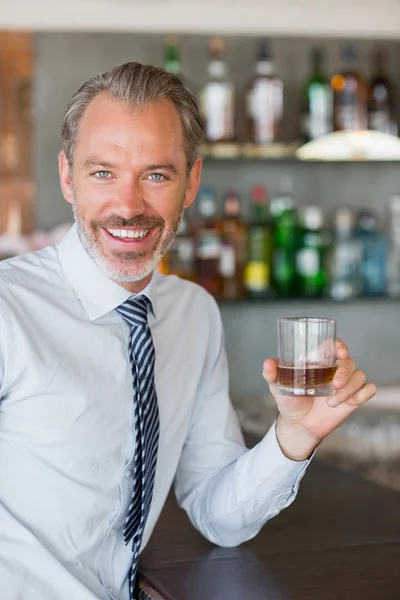 Happy man holding a glass of whiskey — Stock Photo, Image