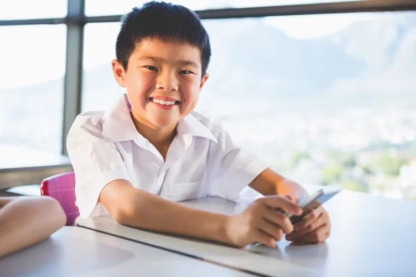 Schoolkid using mobile phone in classroom — Stock Photo, Image