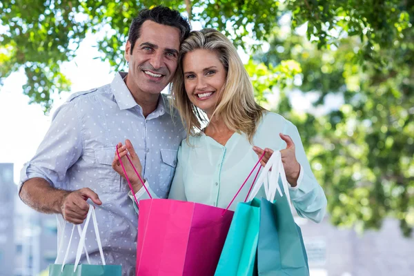 Lachende paar met shopping tassen — Stockfoto
