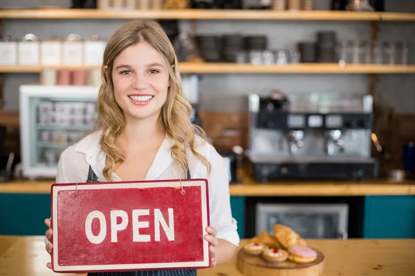 Glimlachend serveerster weergegeven: bord met open teken bij café — Stockfoto