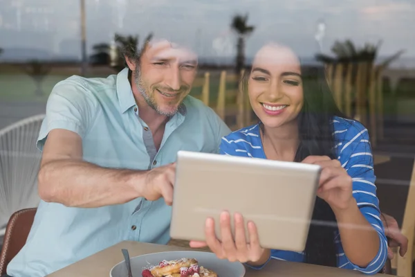 Couple using digital tablet in cafeteria — Stock Photo, Image