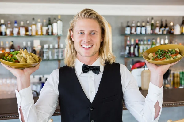 Garçom segurando refeições banhadas no restaurante — Fotografia de Stock