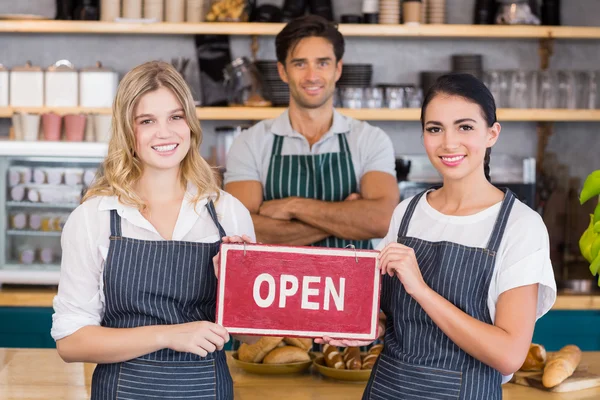 Smiling colleagues showing signboard with open sign — Stock Photo, Image