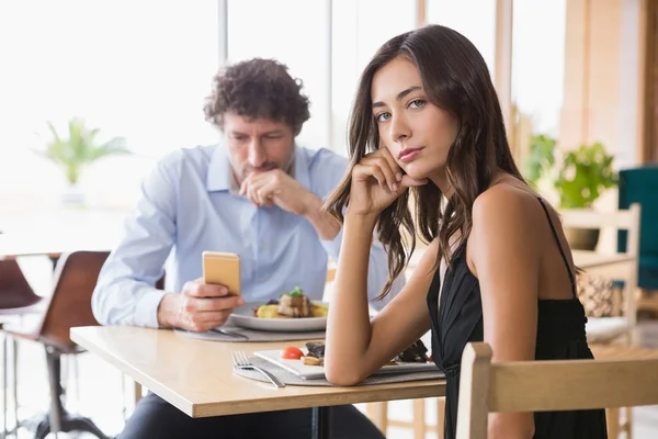 Portrait of woman sitting while man using mobile phone — Stock Photo, Image