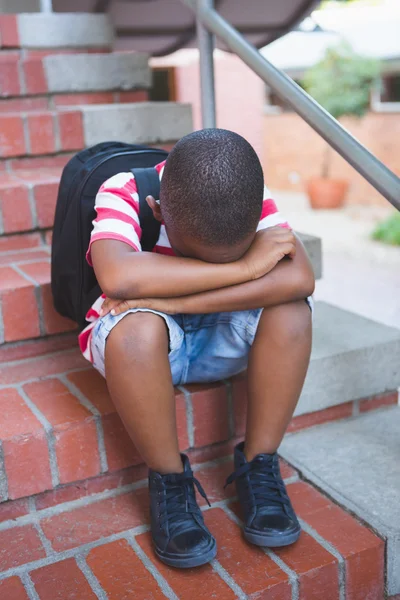 Triste colegial sentado solo en la escalera — Foto de Stock