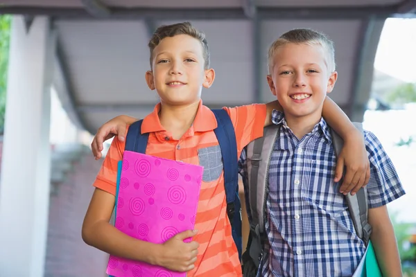 Escolares sonrientes de pie en el pasillo — Foto de Stock