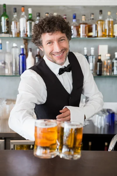 Waiter serving mug of beers — Stock Photo, Image