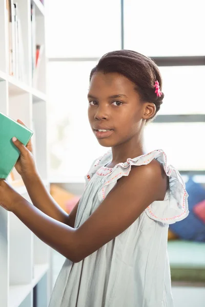 Ragazza che prende un libro dalla libreria in biblioteca — Foto Stock