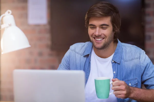 Бизнесмен пьет кофе во время работы над ноутбуком — стоковое фото