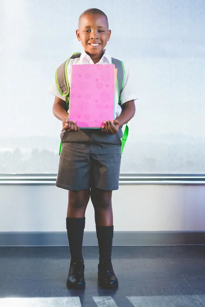 Glad schoolkid hålla böcker och står i klassrummet — Stockfoto