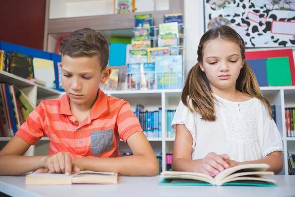 Schoolkids reading book in library — Stock Photo, Image