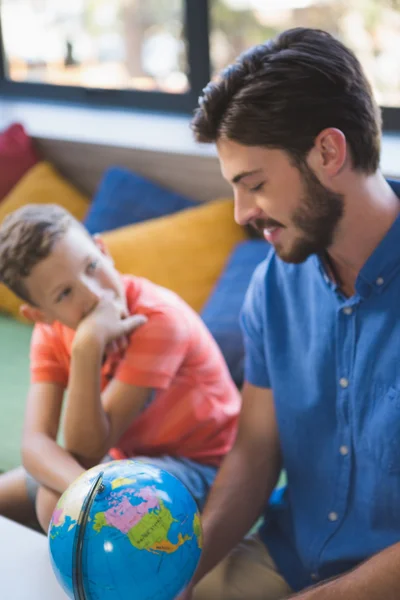 Teacher and kid discussing globe — Stock Photo, Image