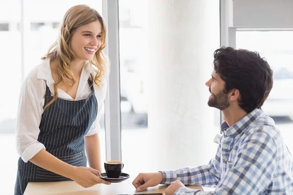 Lächelnde Kellnerin serviert dem Kunden einen Kaffee — Stockfoto