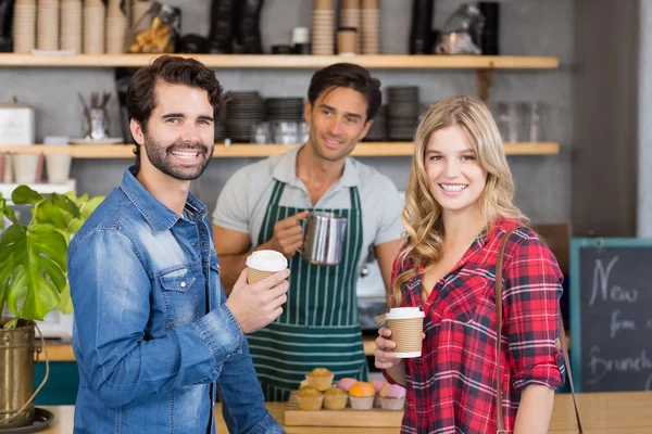 Retrato de pareja sonriente de pie en el mostrador sosteniendo taza de co —  Fotos de Stock