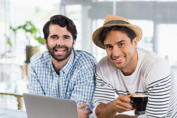 Ritratto di due amici che usano il computer portatile mentre bevono una tazza di caffè — Foto Stock