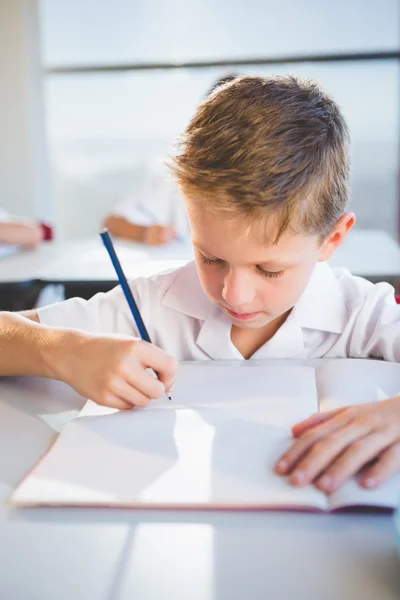 Colegial haciendo tarea en el aula — Foto de Stock