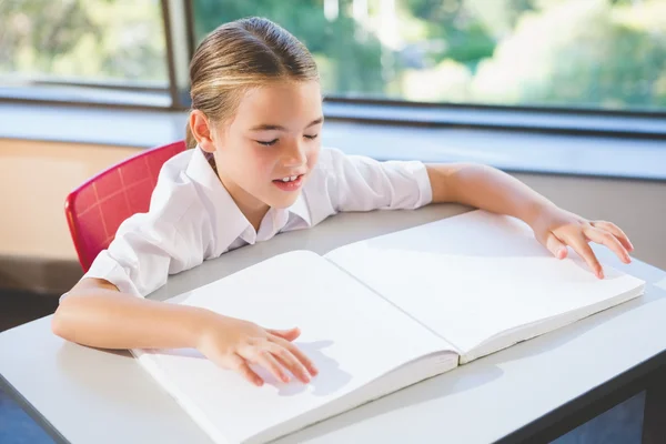 Schoolkid reading braille book in classroom — Stock Photo, Image