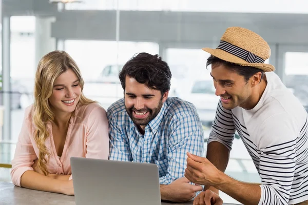 Femme souriante et deux hommes utilisant un ordinateur portable — Photo
