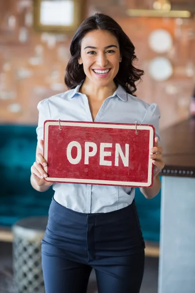 Leende servitris håller en styrelse med öppna tecken i restaurang — Stockfoto