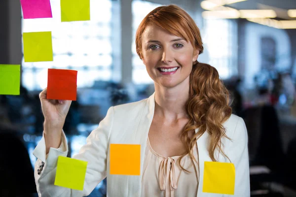 Businesswoman writing on adhesive notes — Stock Photo, Image