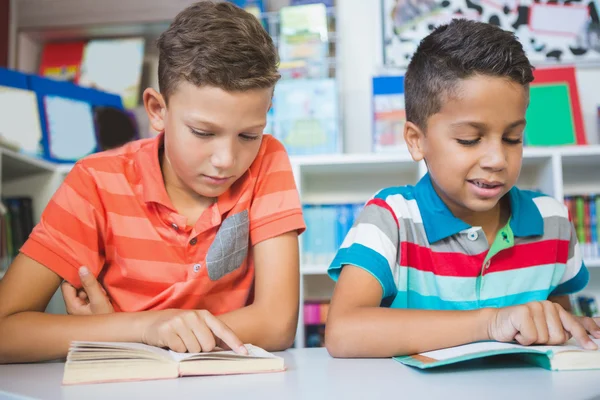 Schoolkids läsa bok i biblioteket — Stockfoto