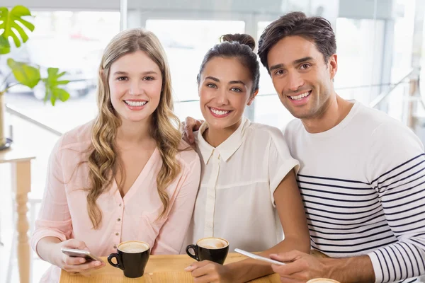 Grupo de amigos usando telefone celular enquanto toma uma xícara de café — Fotografia de Stock