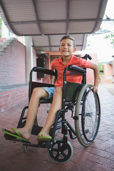 Menino sentado em cadeira de rodas no corredor da escola — Fotografia de Stock