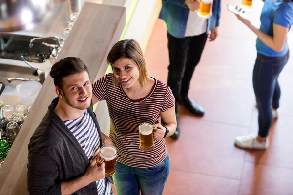 Jovem casal tomando cerveja por balcão — Fotografia de Stock