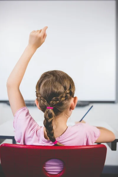 Rückansicht einer Schülerin, die ihre Hand im Klassenzimmer hebt — Stockfoto