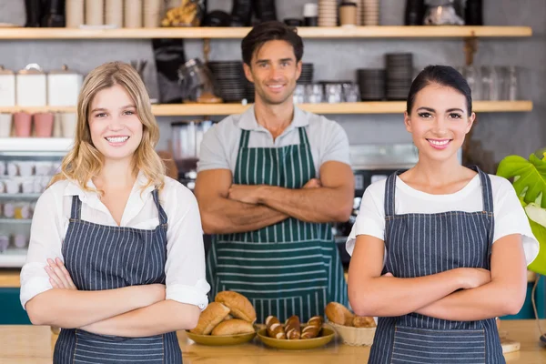 Glimlachend Ober en twee serveersters staand met armen gekruist — Stockfoto