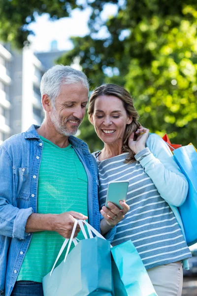 Smiling couple using mobile phone — Stock Photo, Image