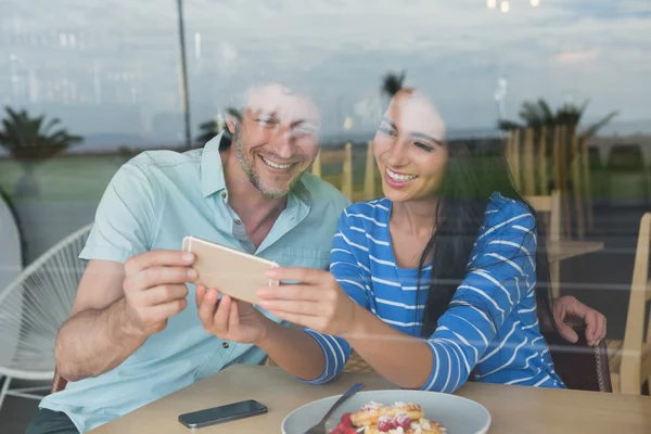 Pareja usando teléfono móvil en cafetería —  Fotos de Stock