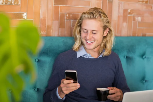 Hombre usando el teléfono móvil mientras toma una taza de café —  Fotos de Stock