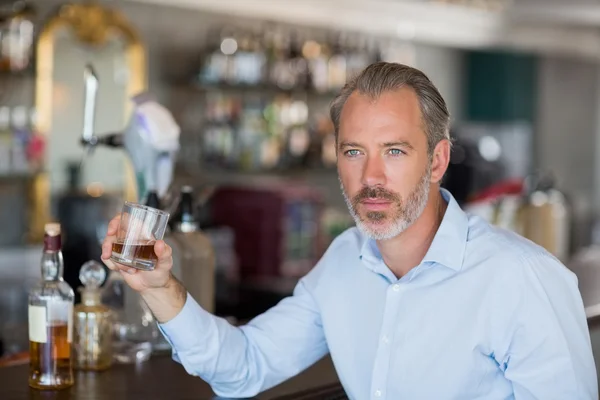 Homme sérieux buvant du whisky au comptoir du bar — Photo