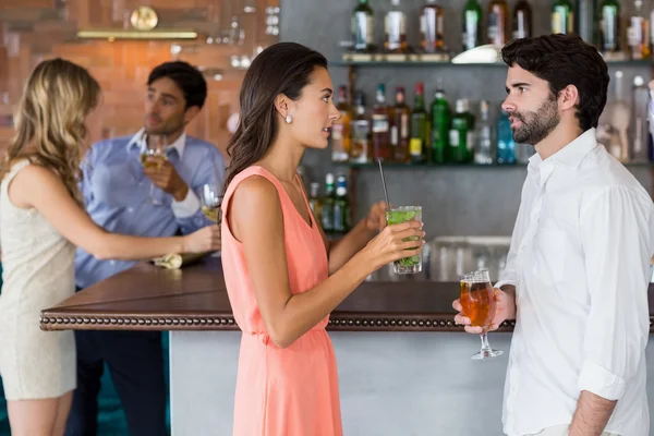 Пара, держащая стакан коктейля перед барной стойкой — стоковое фото