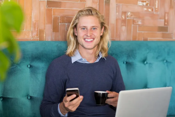 Homem usando telefone celular enquanto toma uma xícara de café — Fotografia de Stock