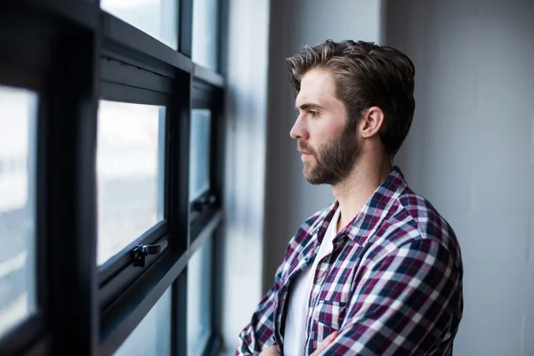 Nadenkende man die door raam — Stockfoto