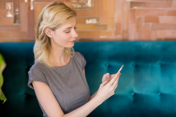 Schöne Frau sitzt auf dem Sofa und benutzt Mobiltelefon — Stockfoto