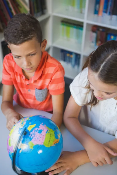 School kids studying globe in library — Stock Photo, Image