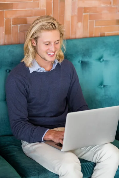 Uomo sorridente utilizzando il computer portatile nel ristorante — Foto Stock