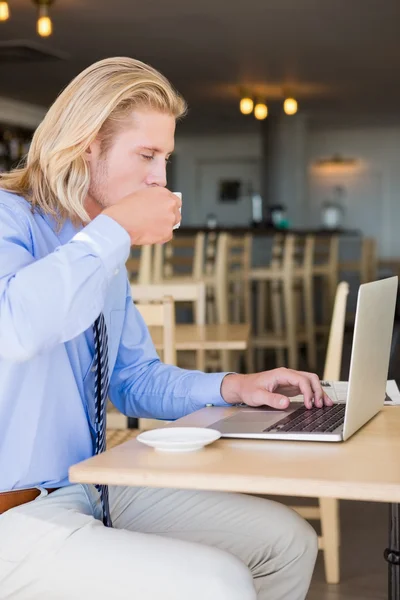 Uomo che prende il caffè mentre usa il computer portatile — Foto Stock
