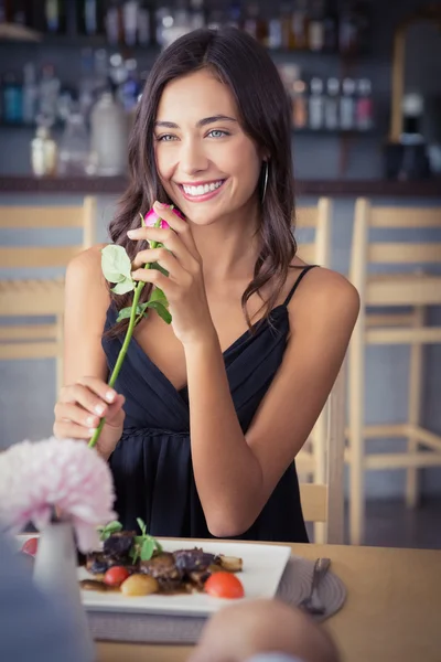 Vacker kvinna med rosa blomma och ler — Stockfoto