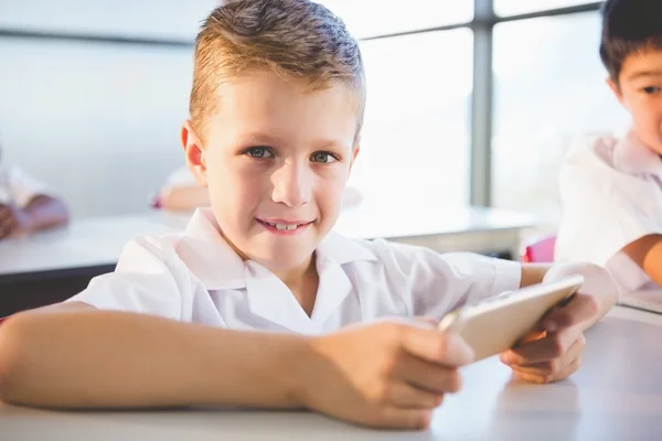 Schoolkid using mobile phone in classroom — Stock Photo, Image