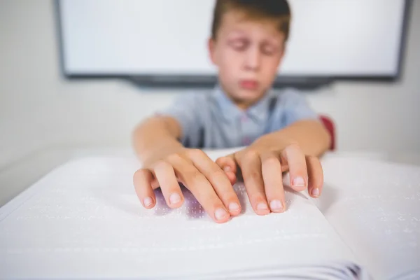 Schoolboy reading a braille book in classroom — Stock Photo, Image