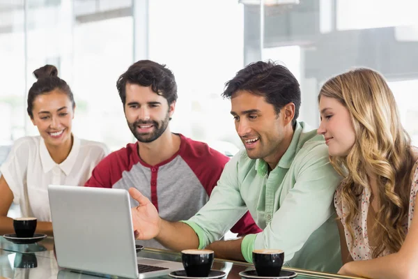 Grupo de amigos usando laptop enquanto toma uma xícara de café — Fotografia de Stock