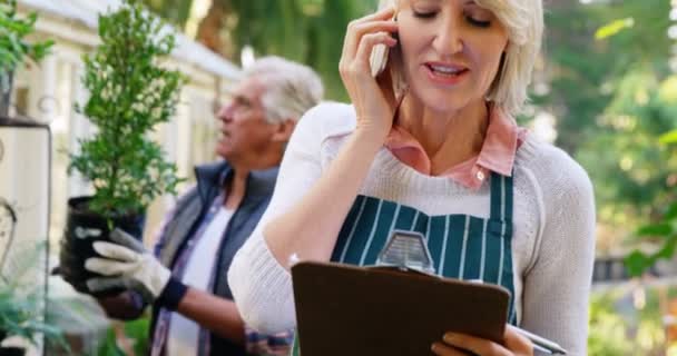 Woman talking on phone while man checking vegetables — Stock Video